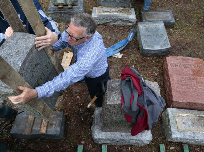 Philip Weiss of Rosenbloom Monument Co. reset headstones at Chesed Shel Emeth Cemetery in University City on Feb. 21, 2017, where almost 200 gravestones were vandalized over the weekend (photo: Robert Cohen/St. Louis Post-Dispatch).